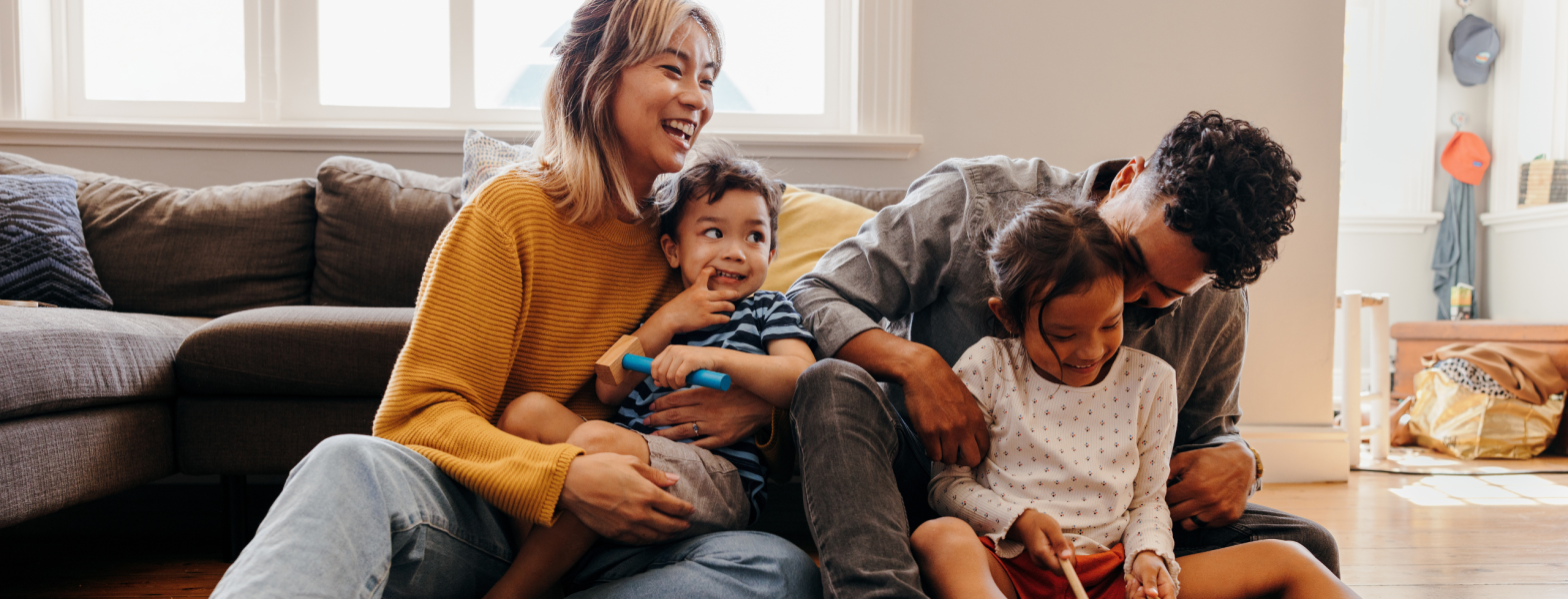 Young parents playing with their son and daughter in the living room. Mom and dad having fun with their children during playtime. Family of four spending some quality time together at home.